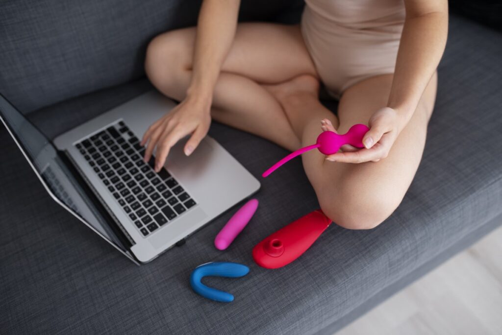 Mulher vendo pornografia no computador com brinquedos sexuais. 