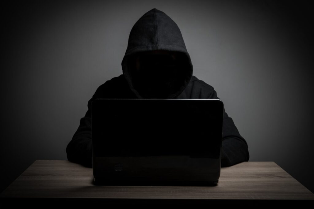Homem anônimo vestido de preto usando um computador preto. 