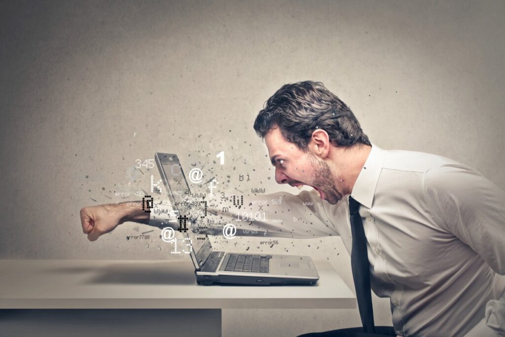 Homem dando soco na tela do computador em desconexão com o mundo real.